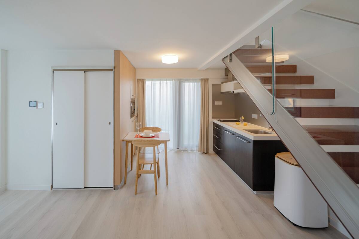 Une cuisine moderne avec un coin repas, un escalier et une porte blanche.