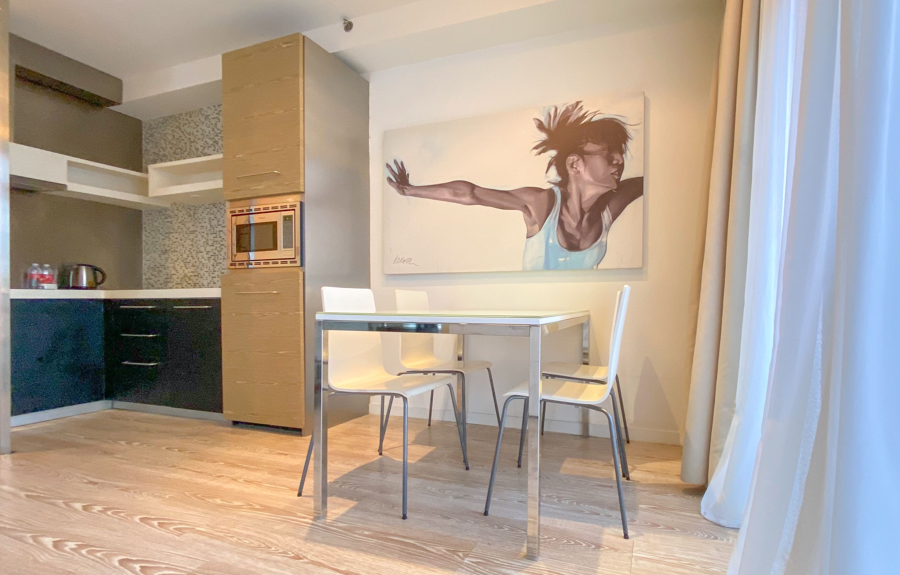 Une cuisine moderne équipée d’un four à micro-ondes, de placards et d’un coin repas avec une table et des chaises.
