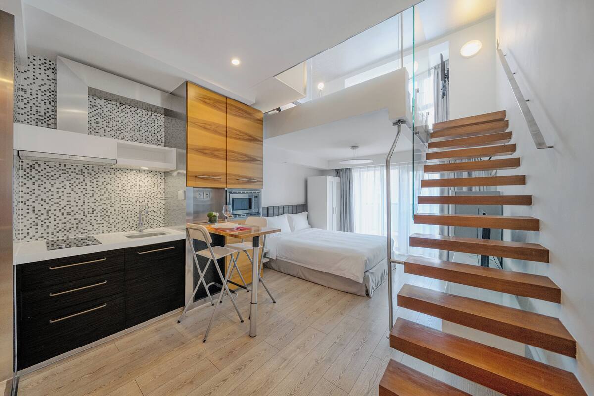 Une chambre d’hôtel moderne dotée d’une cuisine, d’un coin repas et d’un escalier.