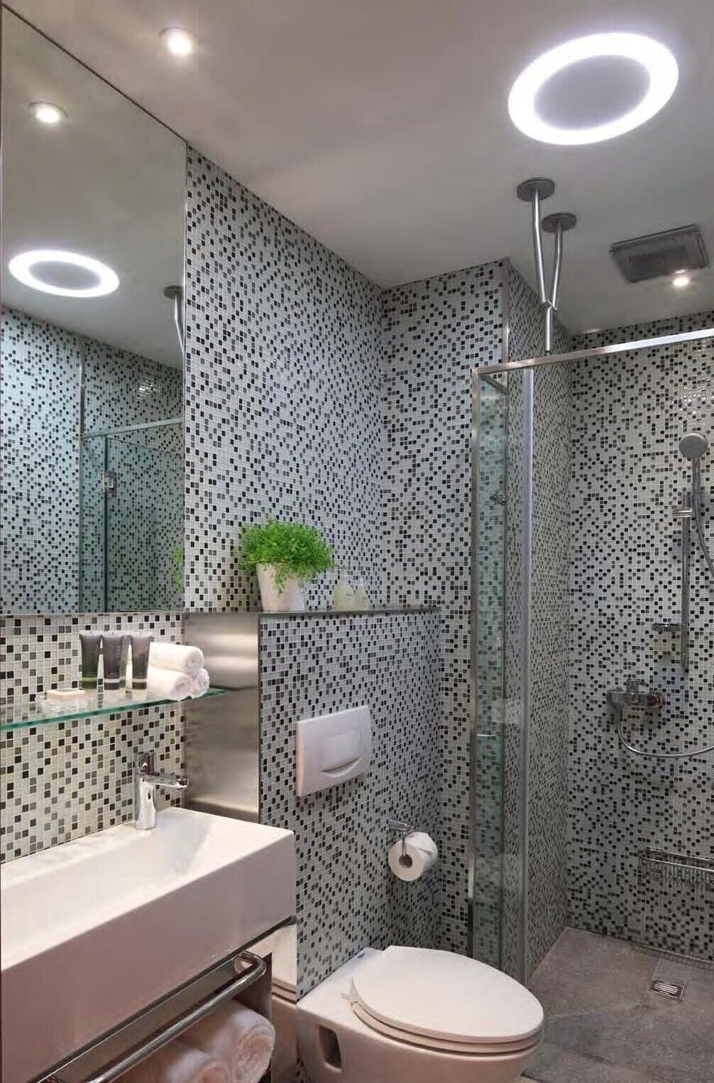 Un baño moderno con cabina de ducha de vidrio, inodoro blanco y lavamanos de vidrio con un espejo encima.