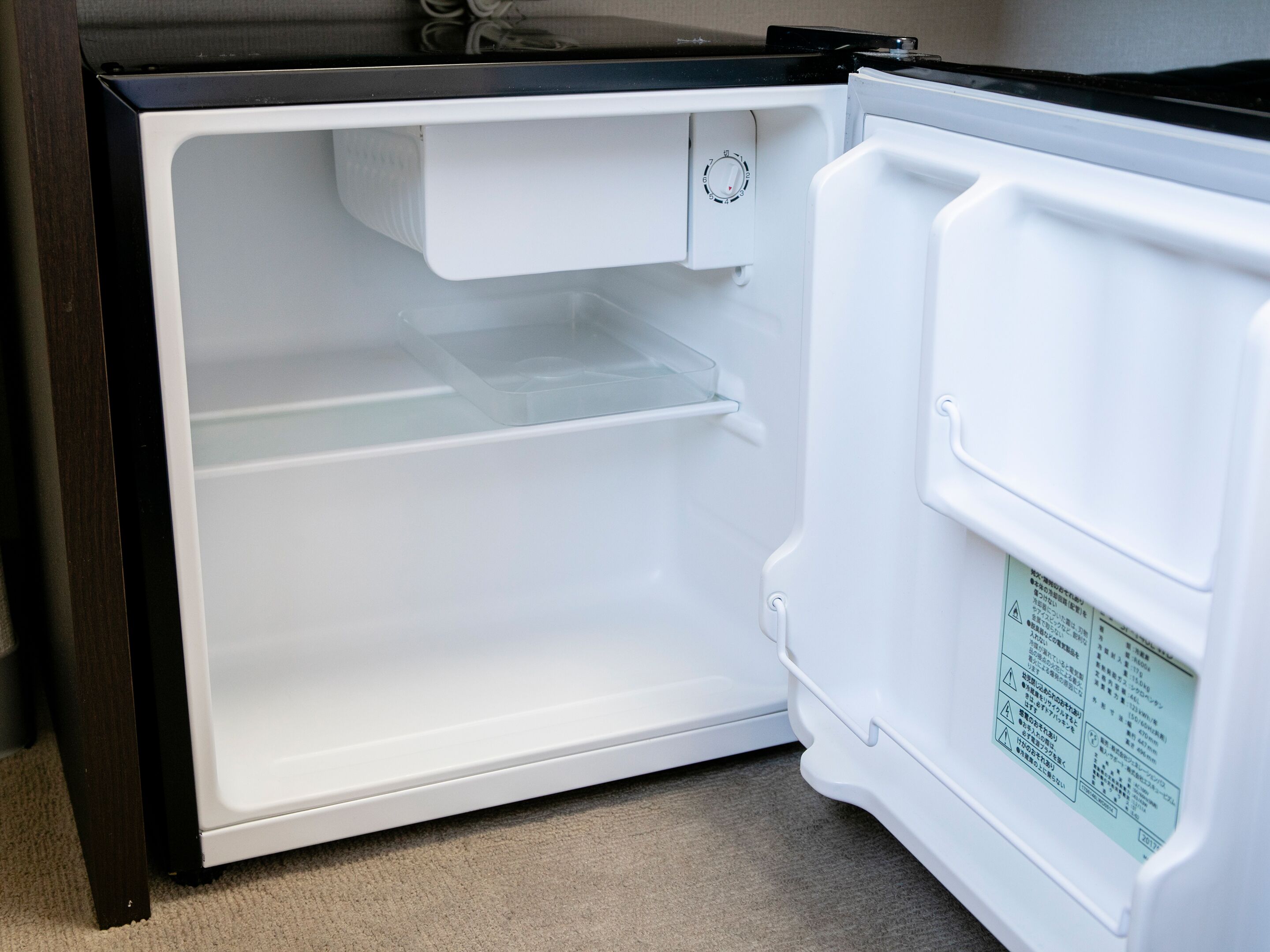 Un refrigerador abierto con un panel de control y una etiqueta de advertencia.