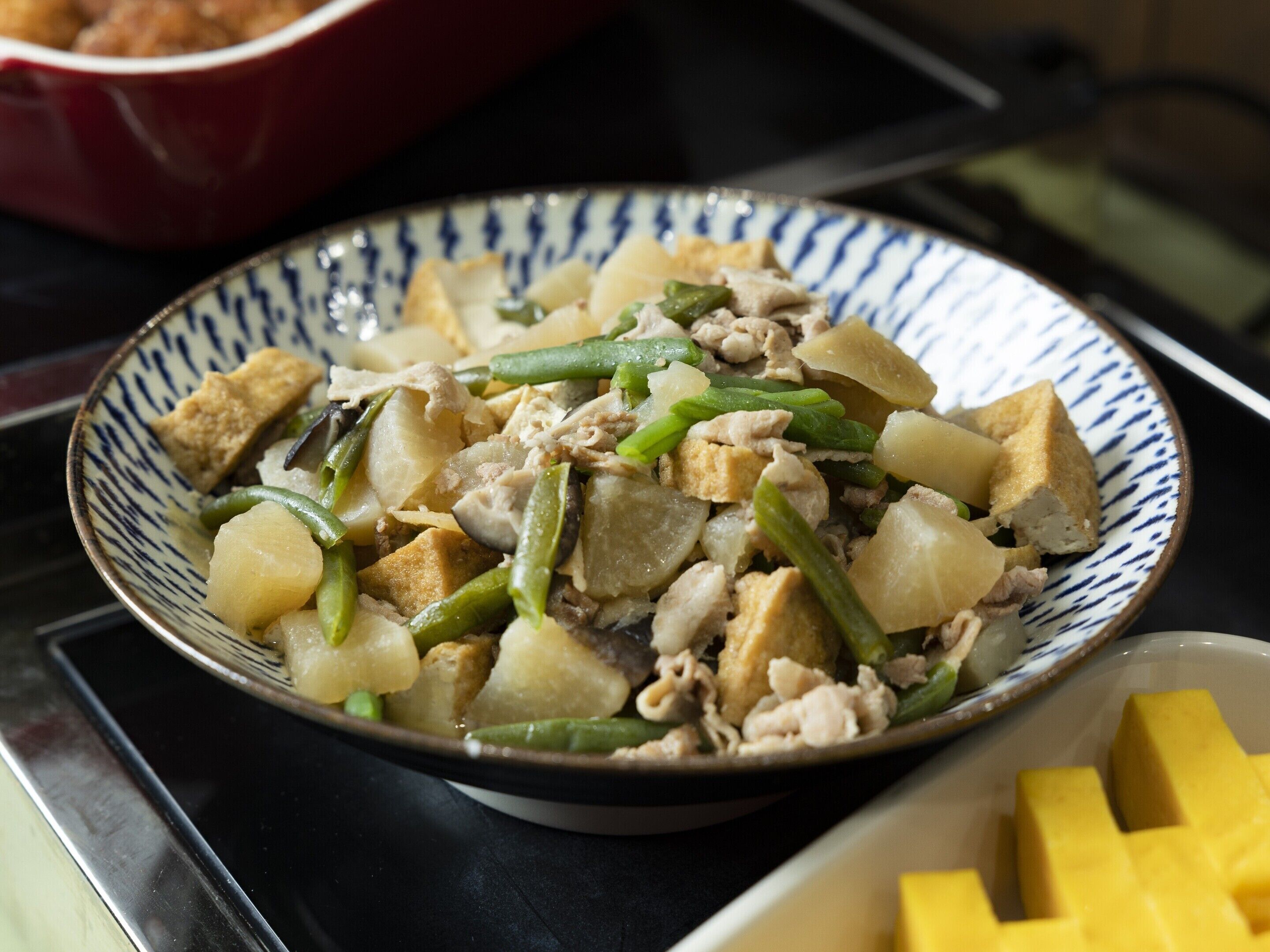 Un tazón de vegetales salteados y tofu sobre una hornalla.