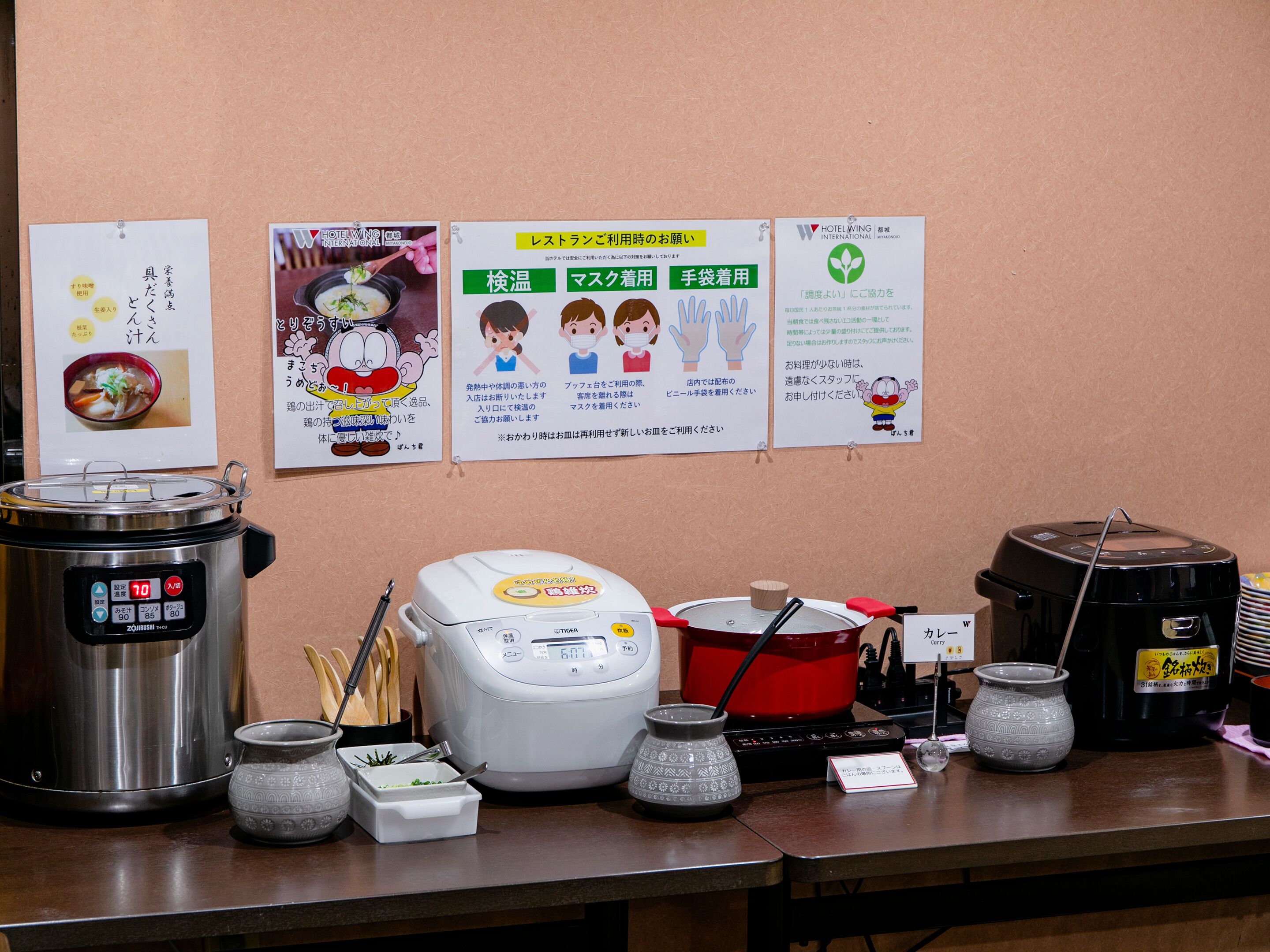 A kitchen area with various cooking appliances and utensils, including a pressure cooker, rice cooker, and pots.