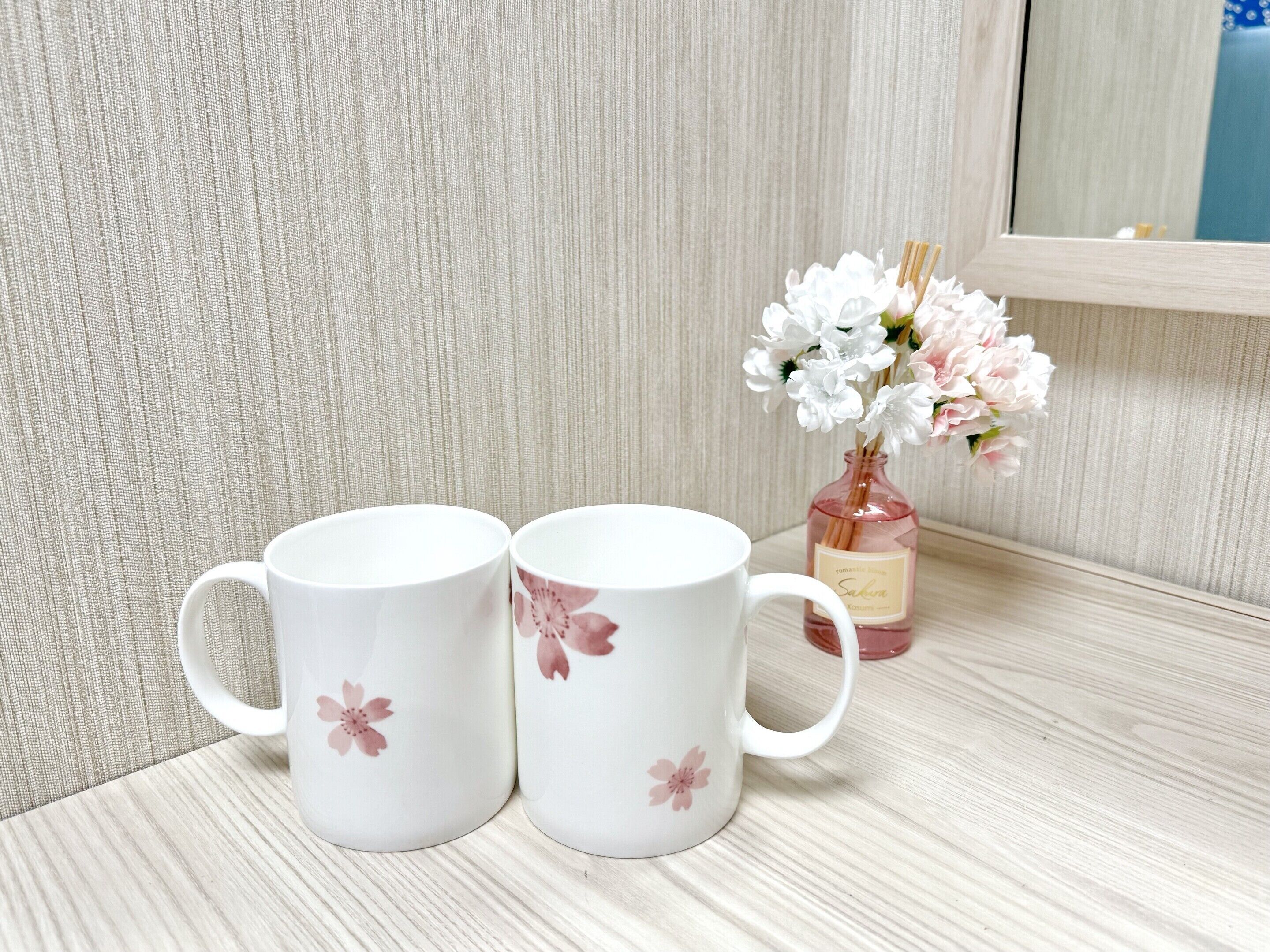 Dos tazas blancas de cerámica con diseños florales sobre una superficie de madera.