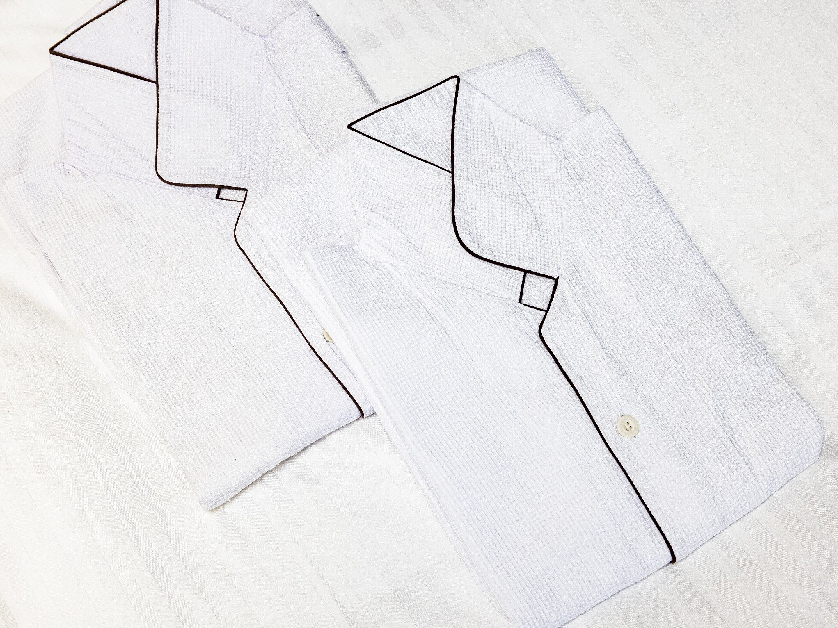 A neatly folded white shirt with a subtle grid pattern and a small button detail on the cuff.