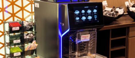 A coffee machine with a digital display, a glass display case with tea packets, and a wooden counter.