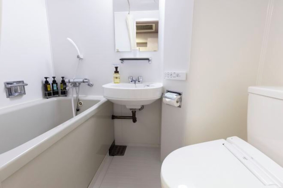 Une petite salle de bain blanche, avec une baignoire, un lavabo et des toilettes.