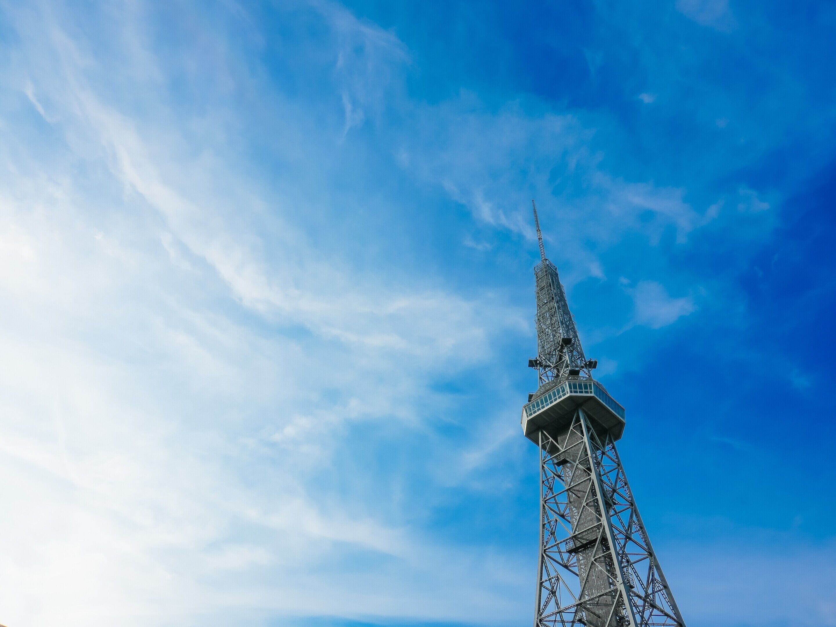 A tall, metal tower with a pointed top against a clear blue sky.