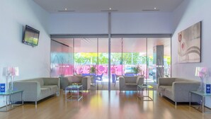 A modern lobby with a glass partition, seating area, and a view of the outside. - Holiday Inn Express Madrid-Leganes by IHG (Leganes)