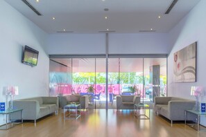 A modern lobby with a glass partition, seating area, and a view of the outside. - Holiday Inn Express Madrid-Leganes by IHG (Leganes)