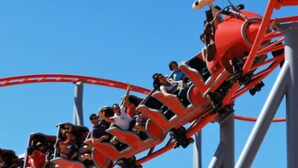 Eine Achterbahn in Bewegung mit sitzenden Fahrgästen in Reihen.