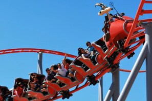 Una montaña rusa en movimiento con pasajeros sentados en filas.