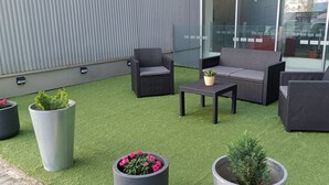 An outdoor seating area with wicker furniture and potted plants on artificial grass. - Holiday Inn Express Madrid-Leganes by IHG (Leganes)