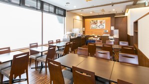 A modern hotel dining area with multiple tables and chairs, a buffet station, and a large window providing natural light. - KOKO STAY Hitachi (Hitachi)