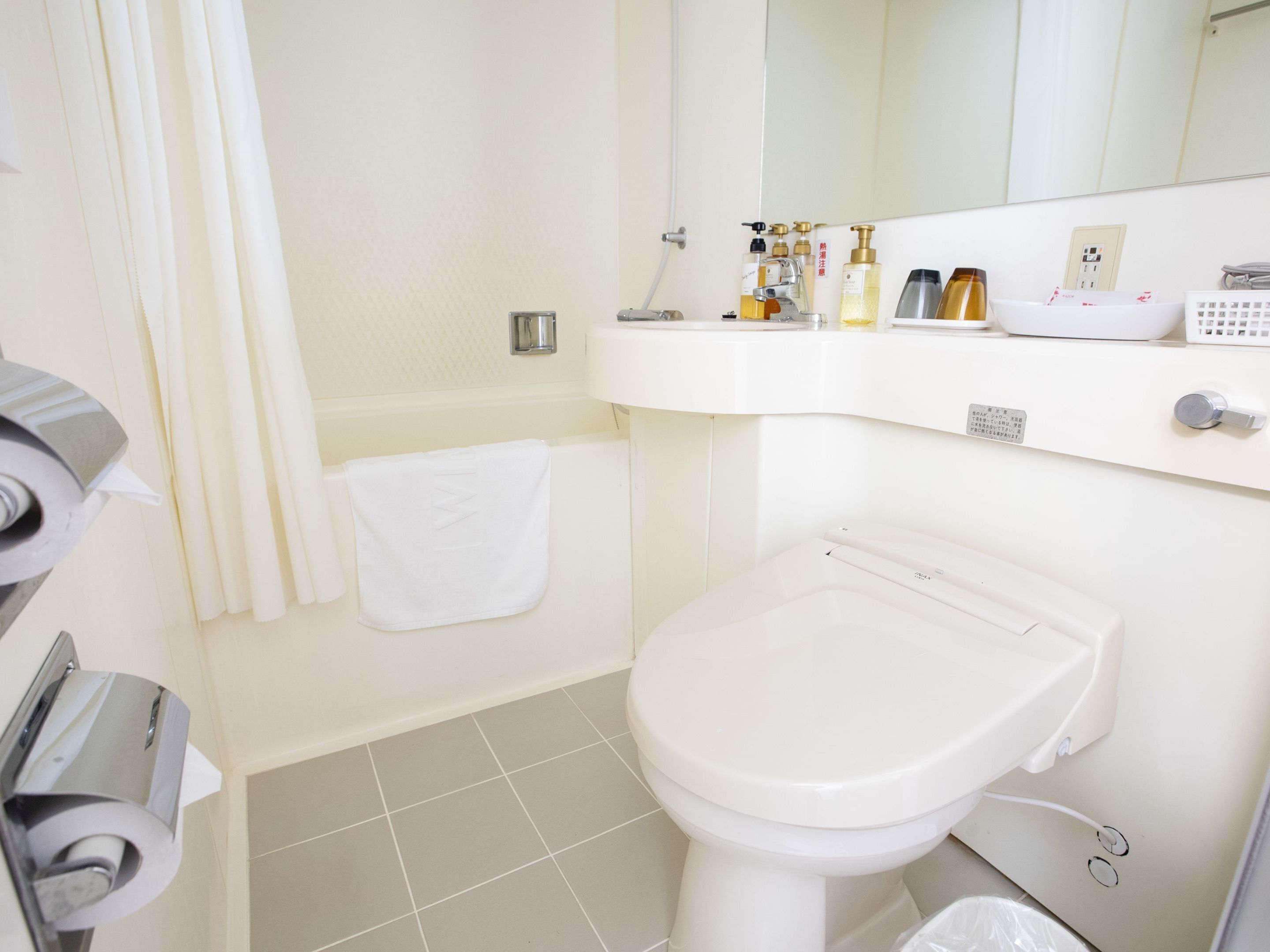 Een badkamer met een toilet, een wastafel, een spiegel en een handdoekhouder.