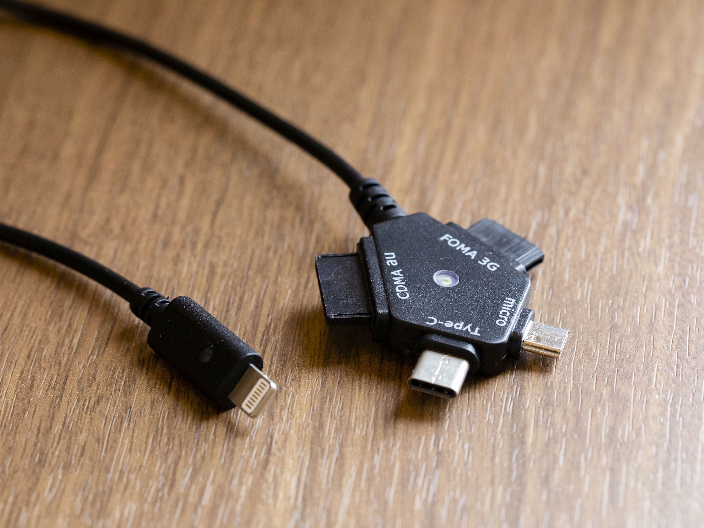 Een USB-C naar USB-A kabel met een Type-C aansluiting en een micro-USB aansluiting, liggend op een houten oppervlak.
