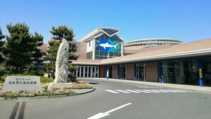 A modern building with a distinctive blue logo, a stone monument, and a clear sky. - KOKO STAY Hitachi (Hitachi)