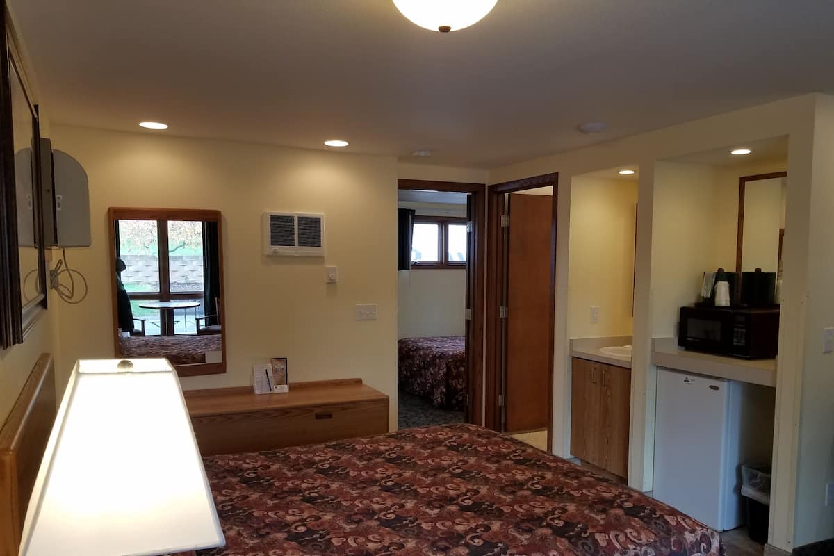 A bedroom with a bed, bedside table, lamp, and a view of a patio area.