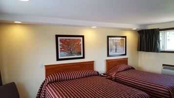 A hotel room with two beds, each with striped bedding, a wooden headboard, and framed pictures on the wall.