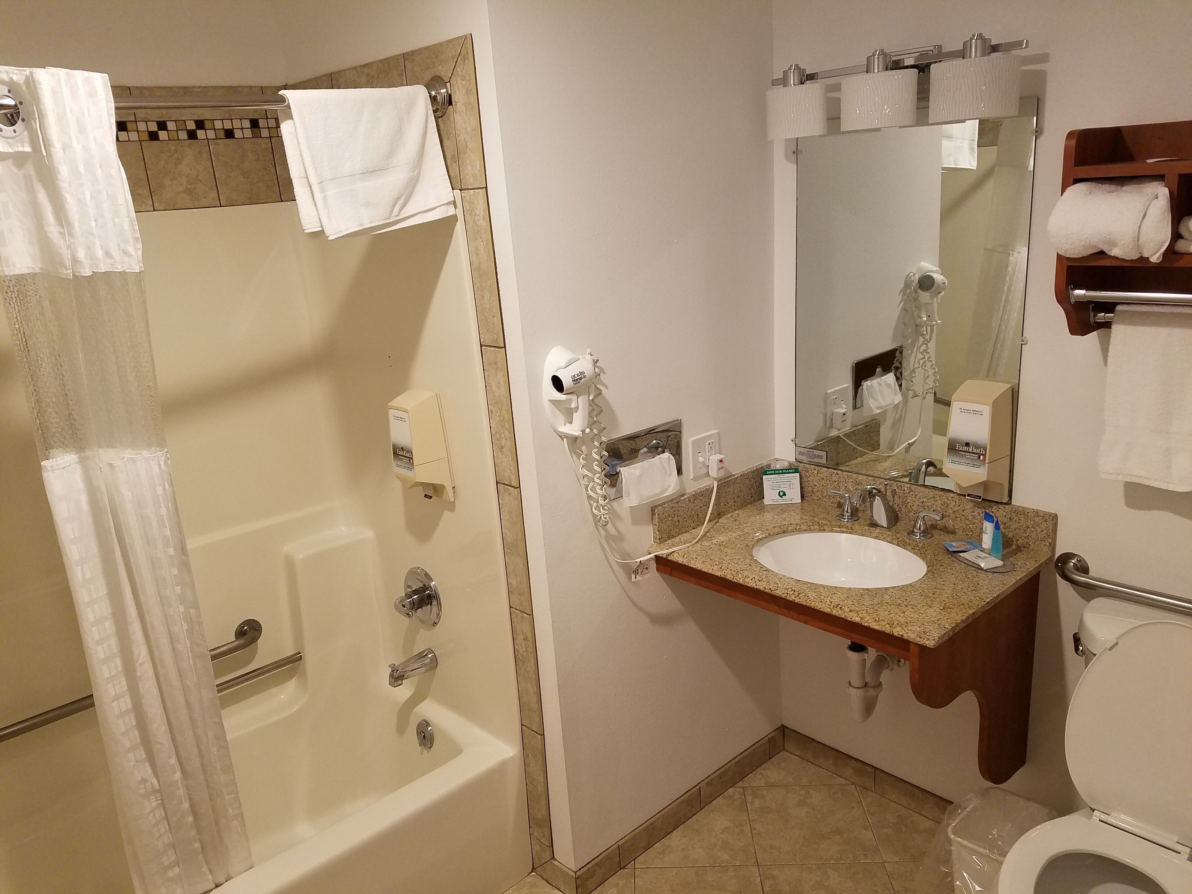 A bathroom with a bathtub, a sink, a toilet, and a mirror.
