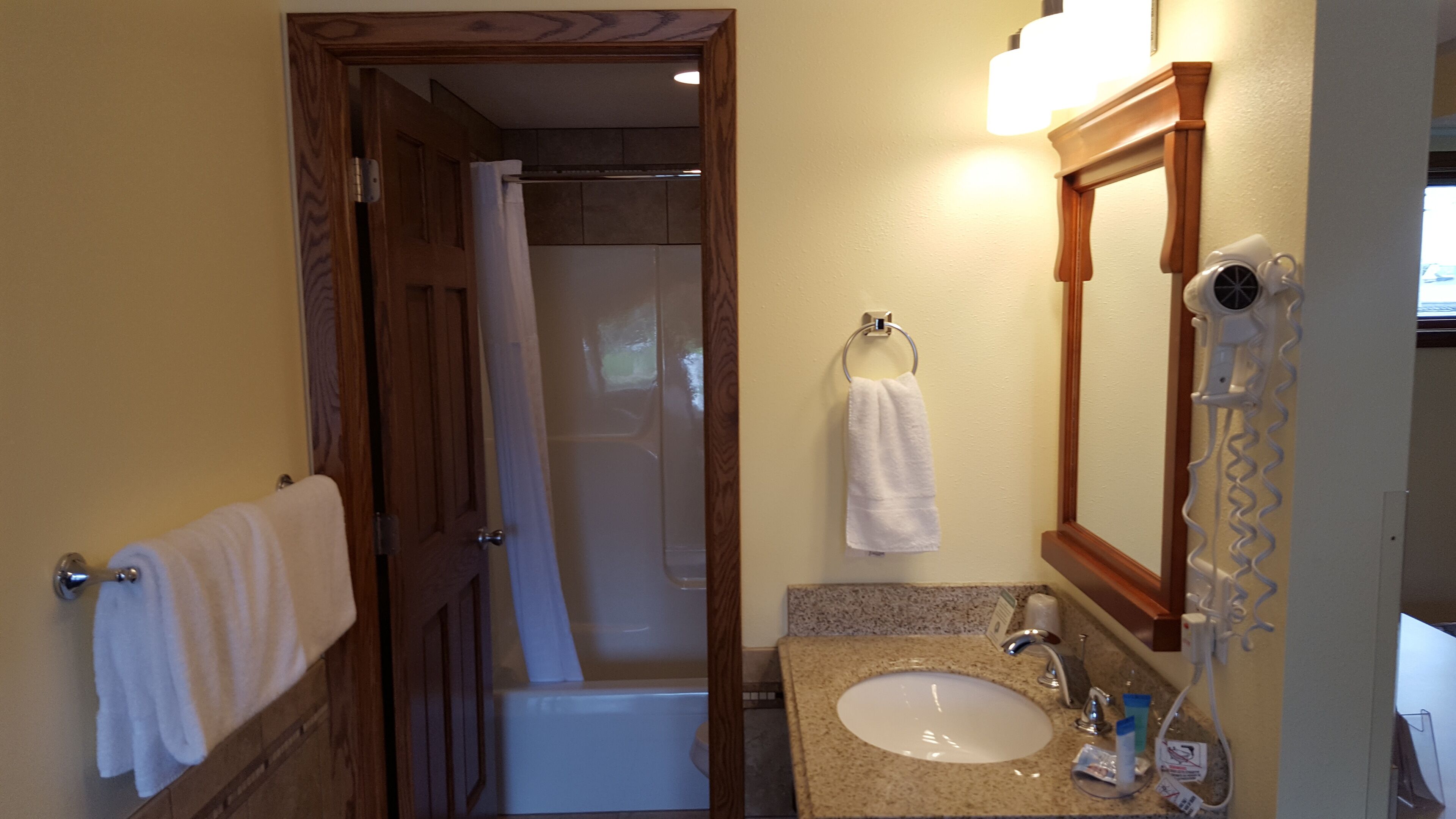 A bathroom with a shower, a sink, a towel rack, and a hairdryer.