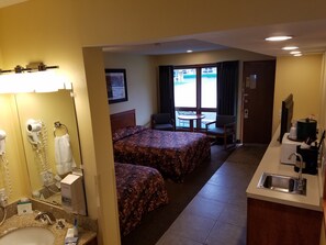 Habitación de hotel con cama, escritorio, lavamanos y ventana con vista al exterior.