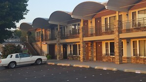Un hotel de varios pisos con fachada de piedra, balcones y zonas de estar al aire libre.