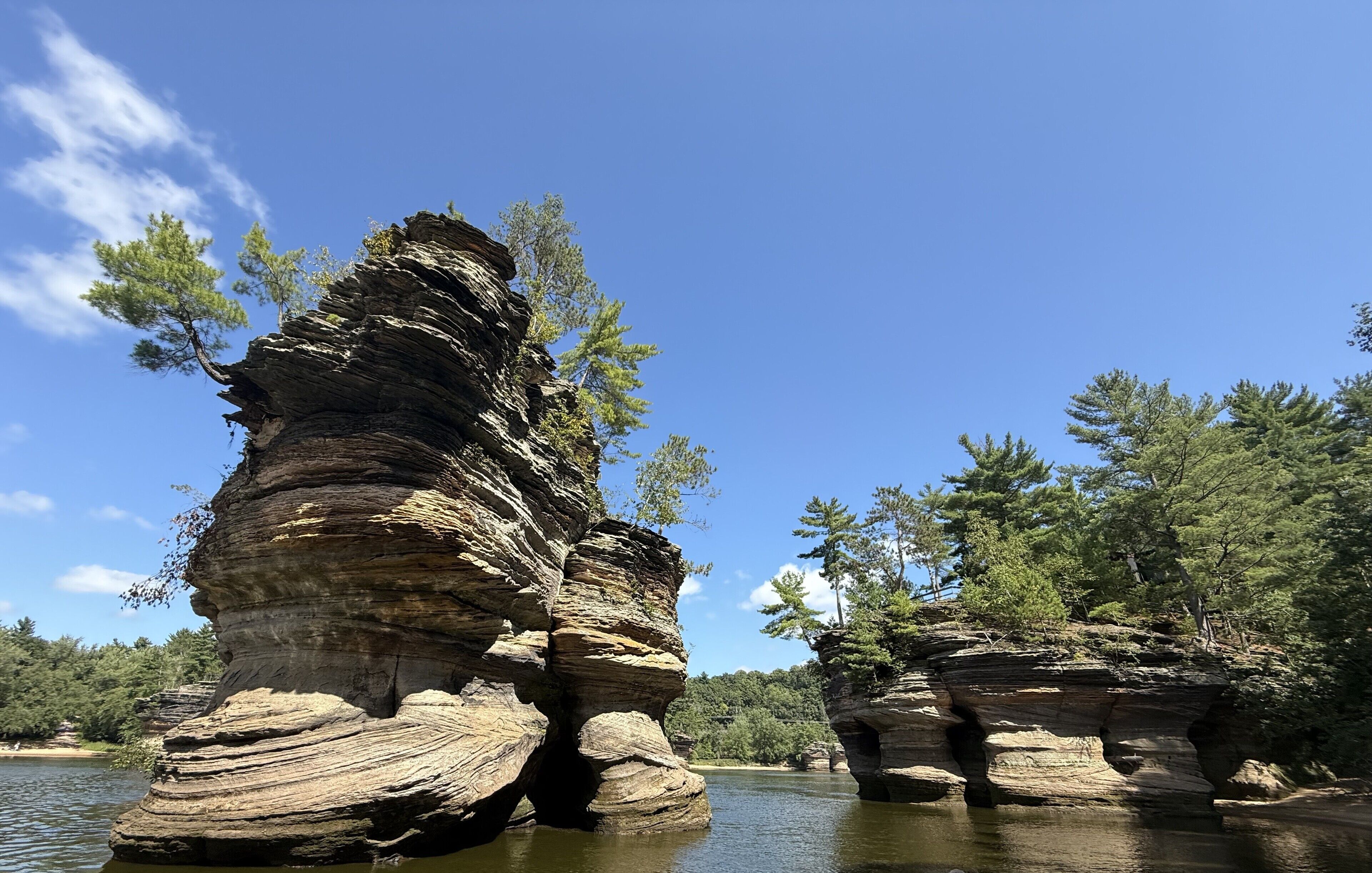 A natural rock formation with water in front of it.