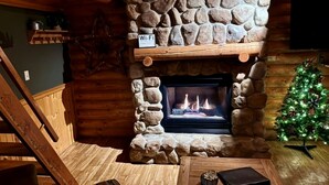 A cozy cabin interior with a stone fireplace, a wooden staircase, a Christmas tree, and a Wi-Fi sign. - Cedar Lodge and Settlement (Wisconsin Dells)