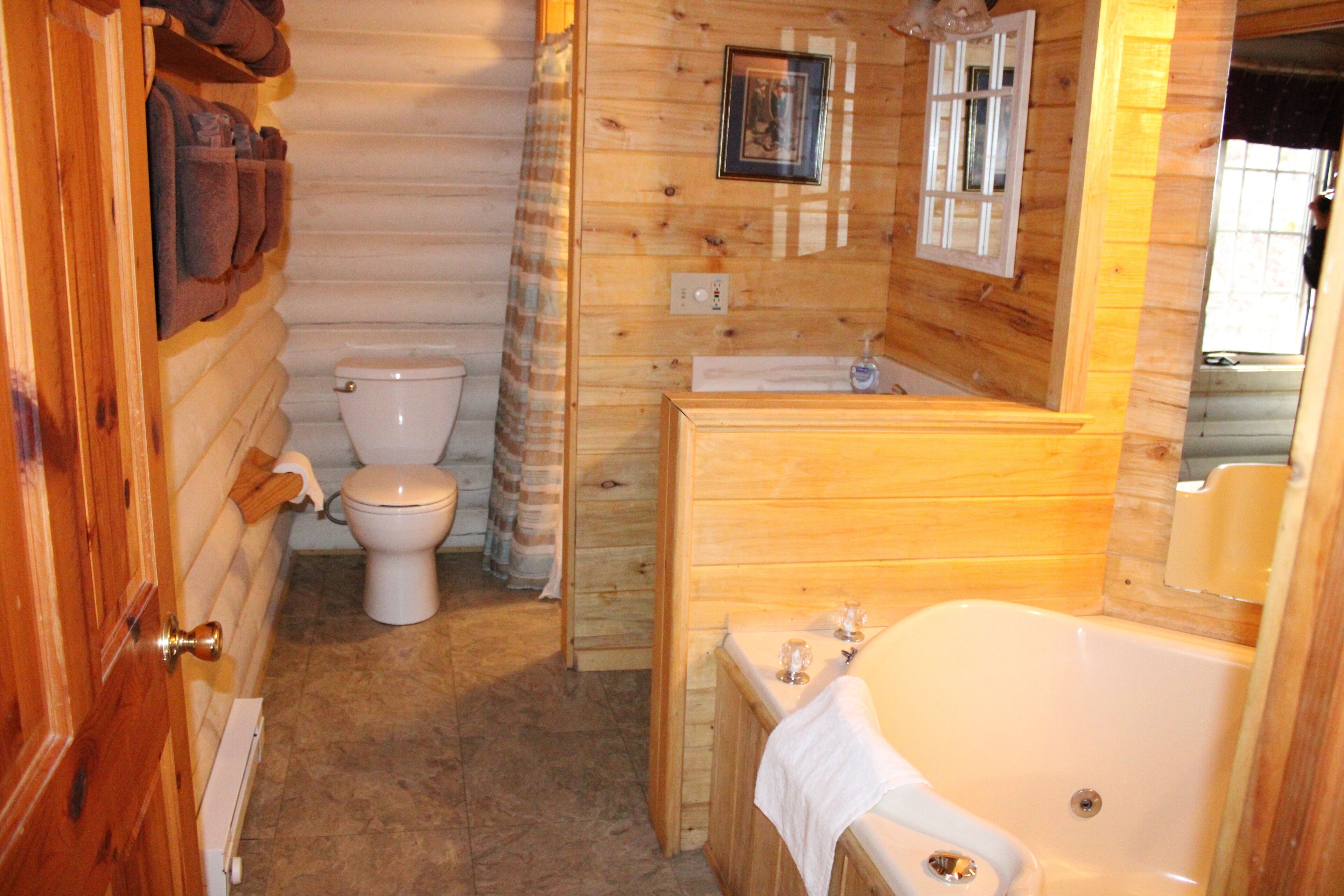 A wooden cabin bathroom with a toilet, sink, and bathtub.