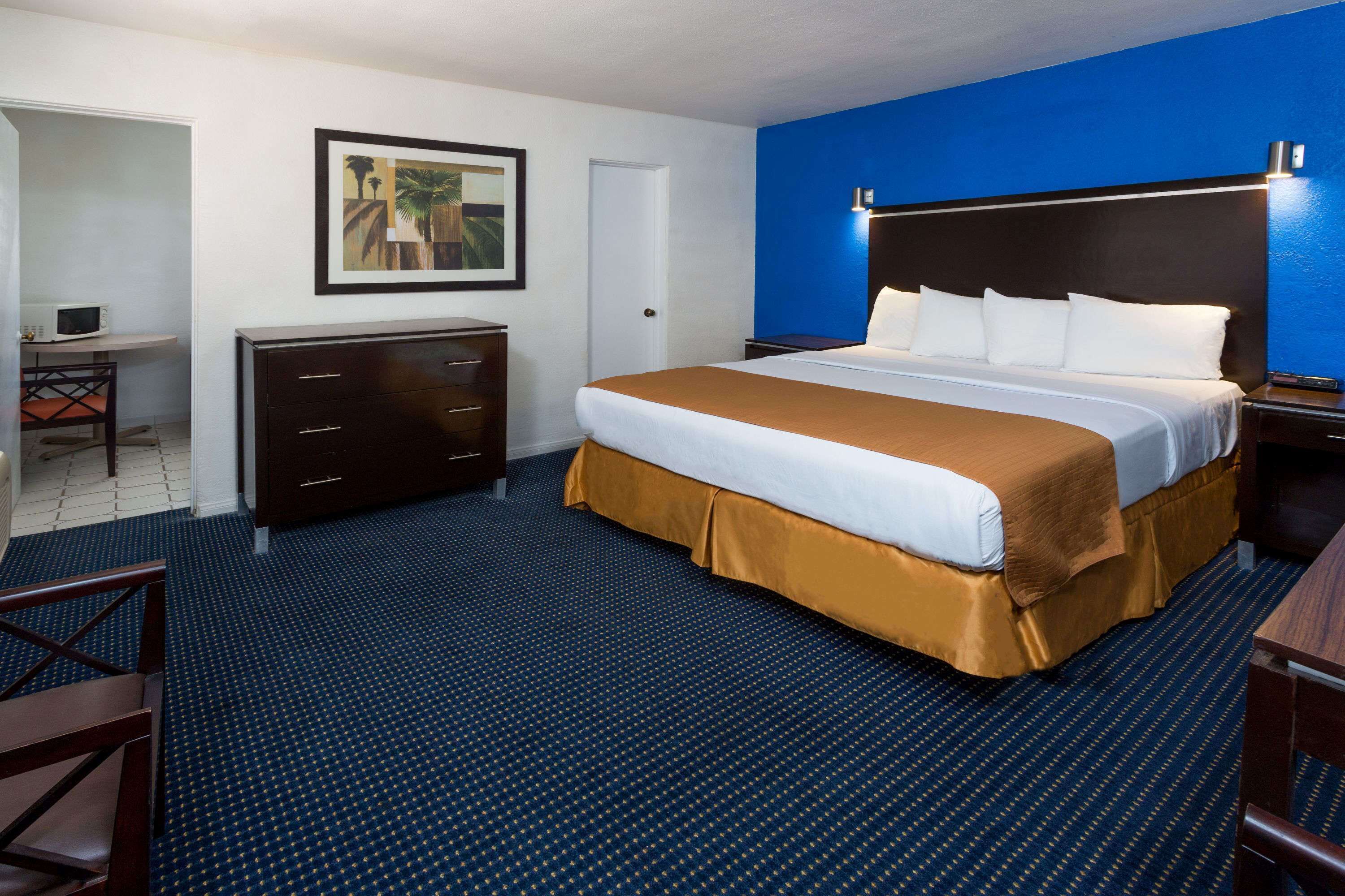 Une chambre d’hôtel avec un grand lit, un bureau, une commode et un tableau encadré au mur.