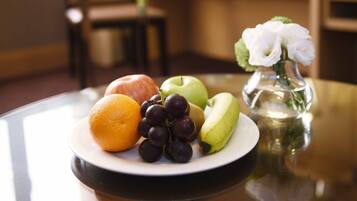 A plate with an apple, kiwi, orange, grapes, and a banana on a table.