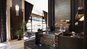Un espace bar moderne doté d’un comptoir en marbre, d’une vitrine réfrigérée et d’une machine à café.