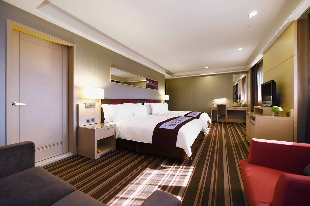 Ein Hotelzimmer mit einem großen Bett, einem Schreibtisch, einem Stuhl, einem Fernseher und einem Badezimmer.