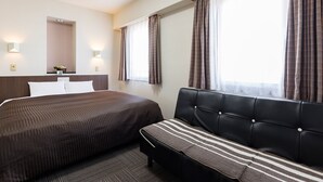 Una habitación de hotel con cama, sofá, ventana con cortinas e iluminación en la pared.