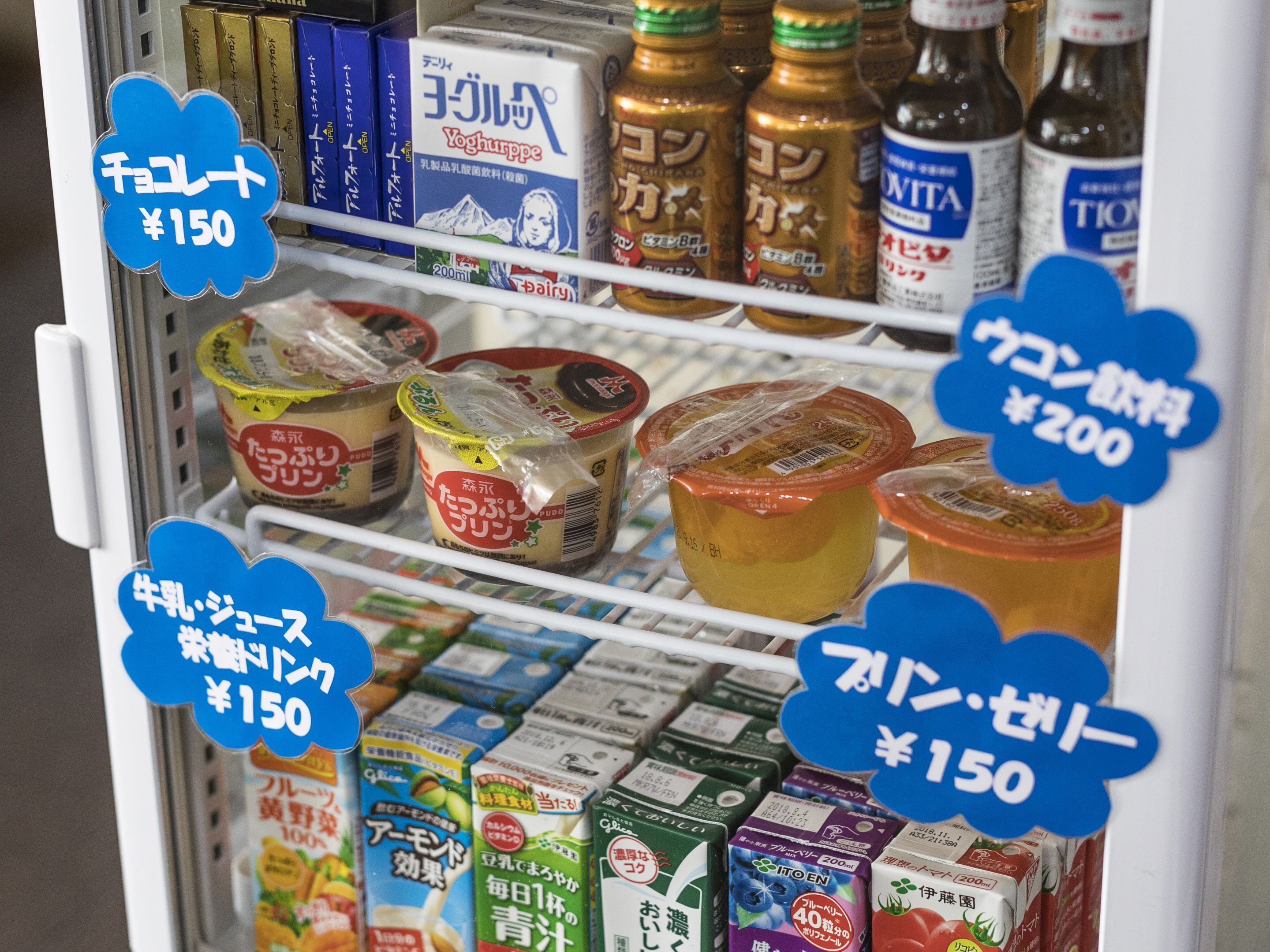 Een gekoelde vitrine met diverse zuiverproducten en dranken, inclusief geprijsde labels.