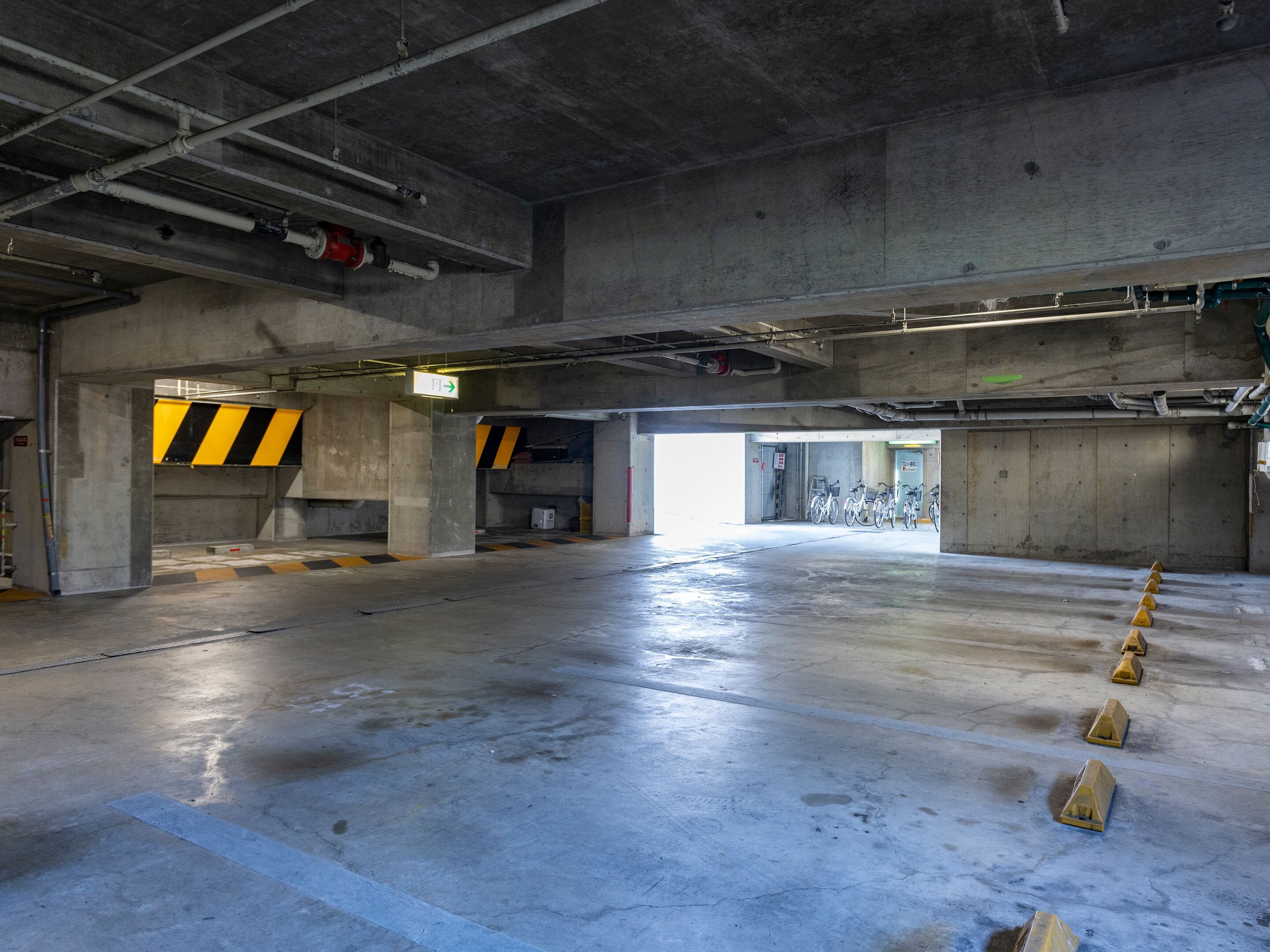 A spacious underground parking garage with concrete walls, a clean floor, and a few bicycles parked.