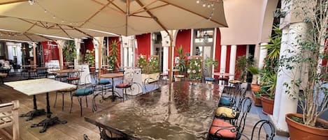 Un café intérieur avec des tables et des chaises, des guirlandes lumineuses et des plantes en pot.