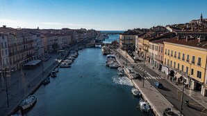 A canal lined with boats and buildings, a bridge, and a clear sky.