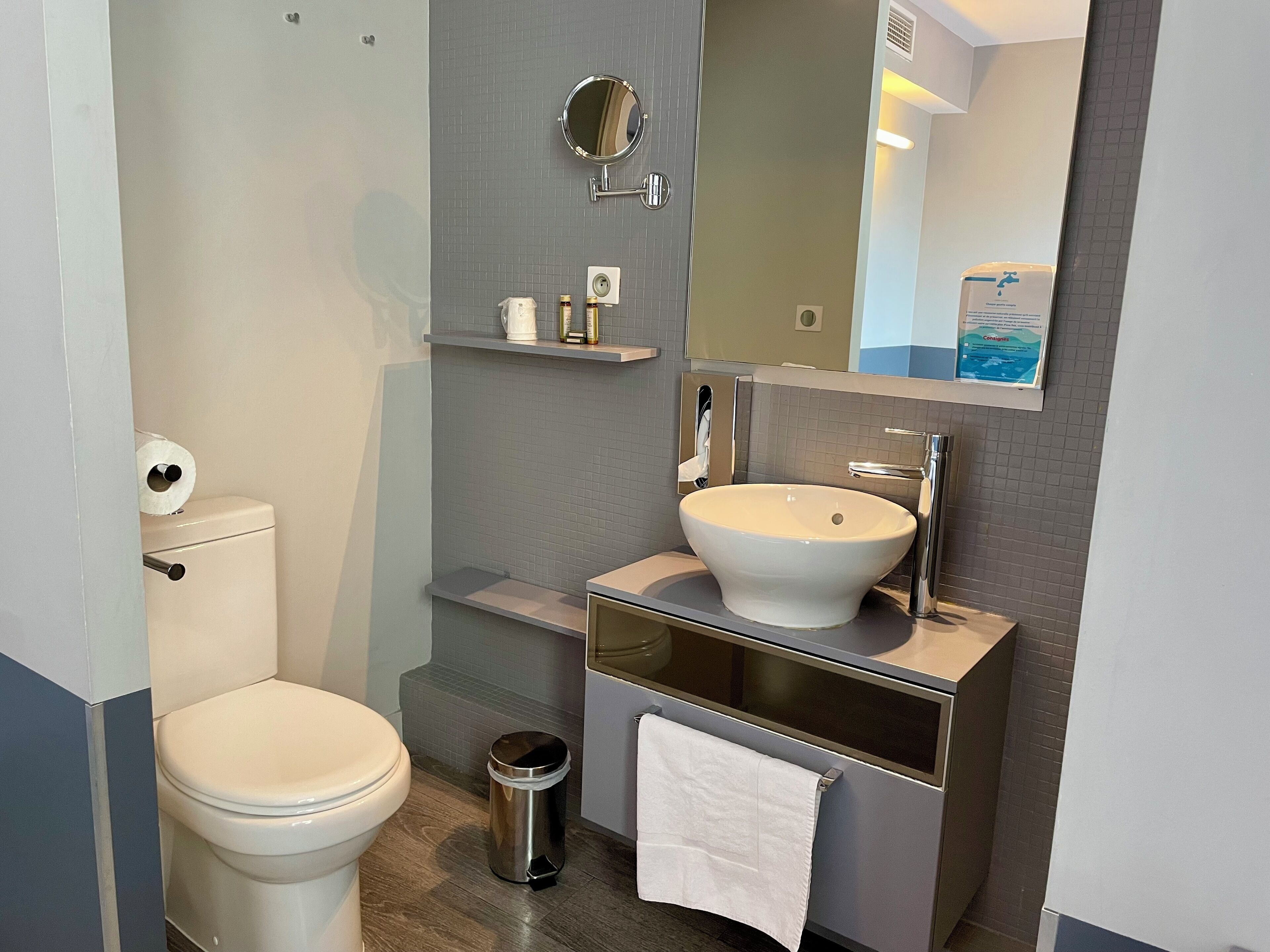 Un bagno moderno con il water, un lavandino, uno specchio e un cestino.