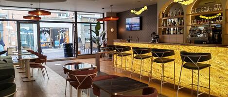 Un espace bar avec des sièges, un comptoir avec une caisse enregistreuse et un écran de télévision.