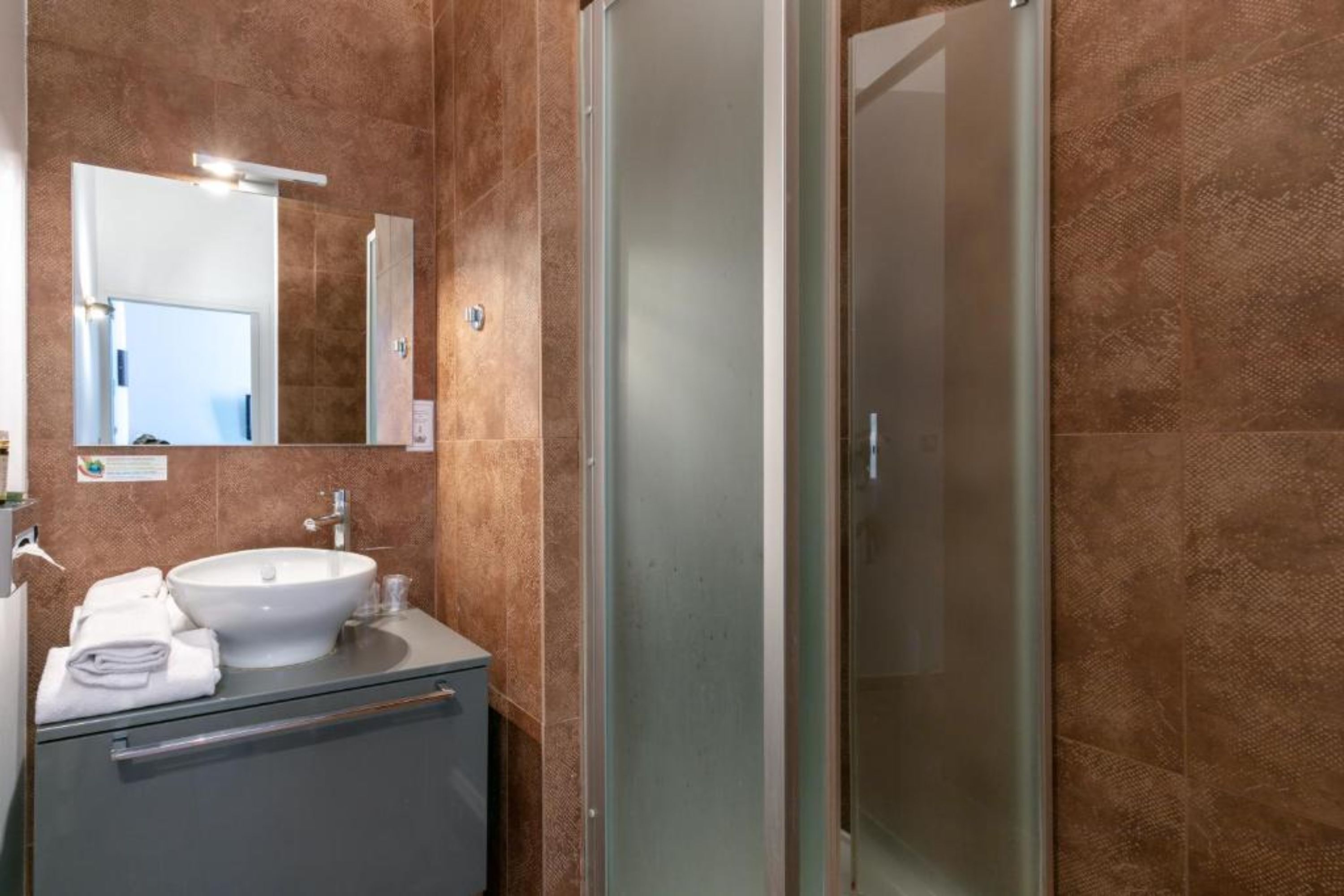 Un baño con lavamanos, espejo y cabina de ducha de vidrio.