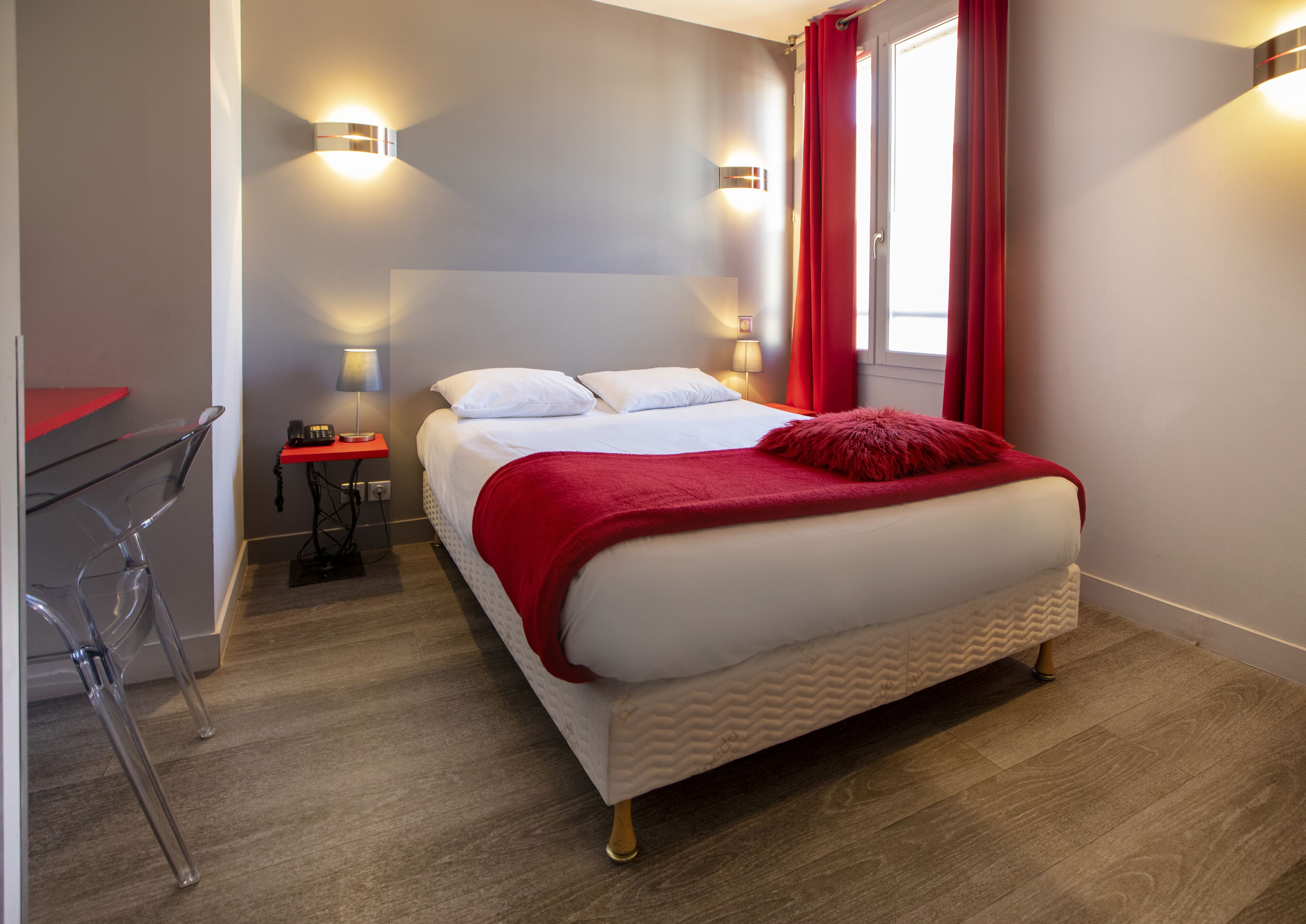 A modern hotel room with a large bed, a desk, and a chair.