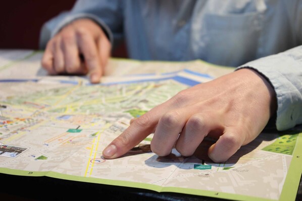 A hand pointing at a map with various streets and locations marked.