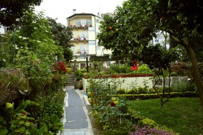 A garden pathway leading to a building with balconies and a well-maintained lawn. - Hotel Estoril Porto (Porto)