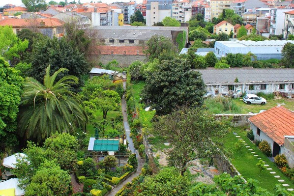 A residential area with a mix of modern and older buildings, a well-maintained garden with a pathway, and a parked car. - Hotel Estoril Porto (Porto)