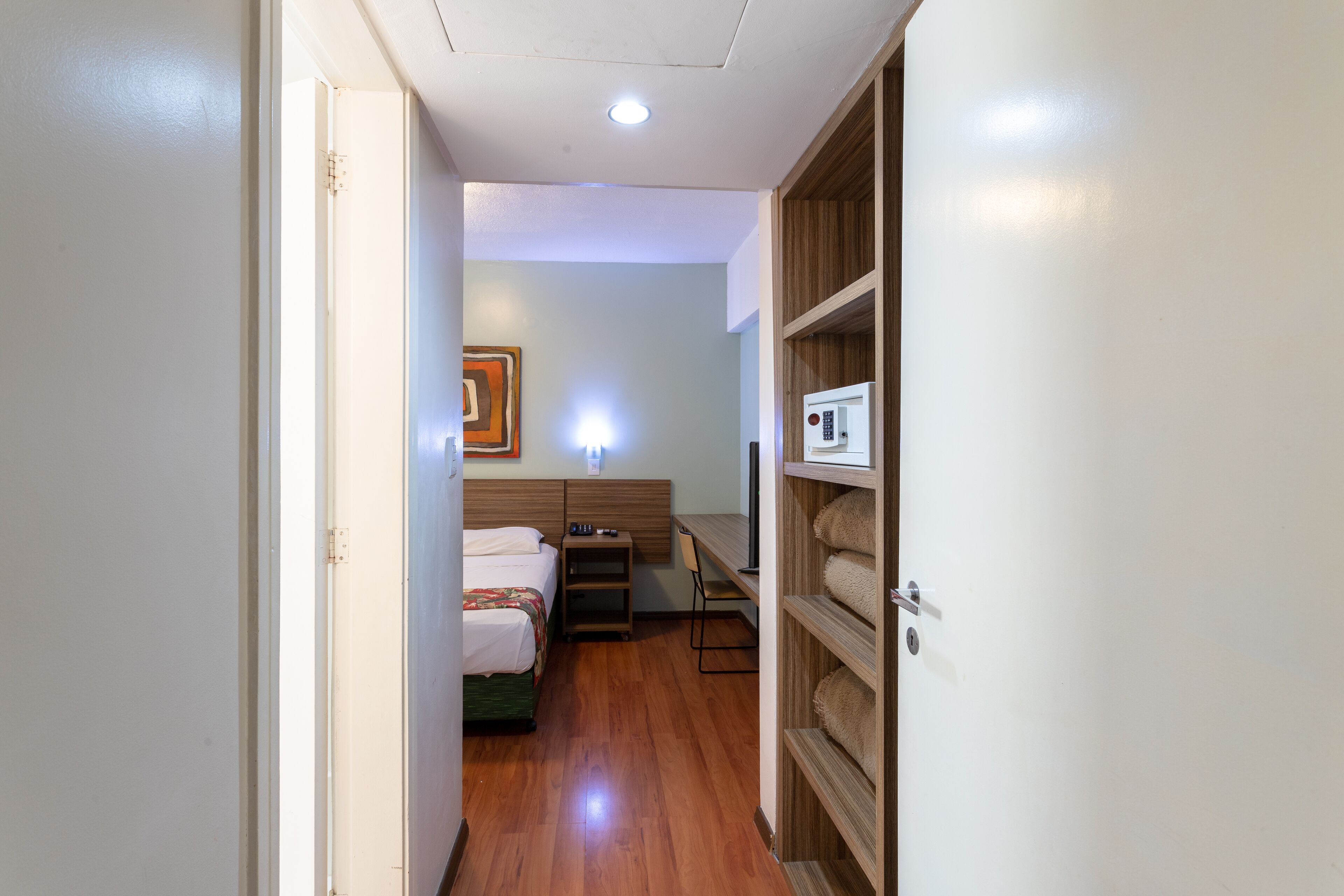 Una habitación de hotel con cama, escritorio, silla y armario.