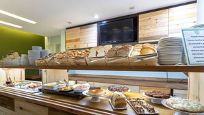 Un mostrador de buffet con diversos alimentos y un televisor encima.