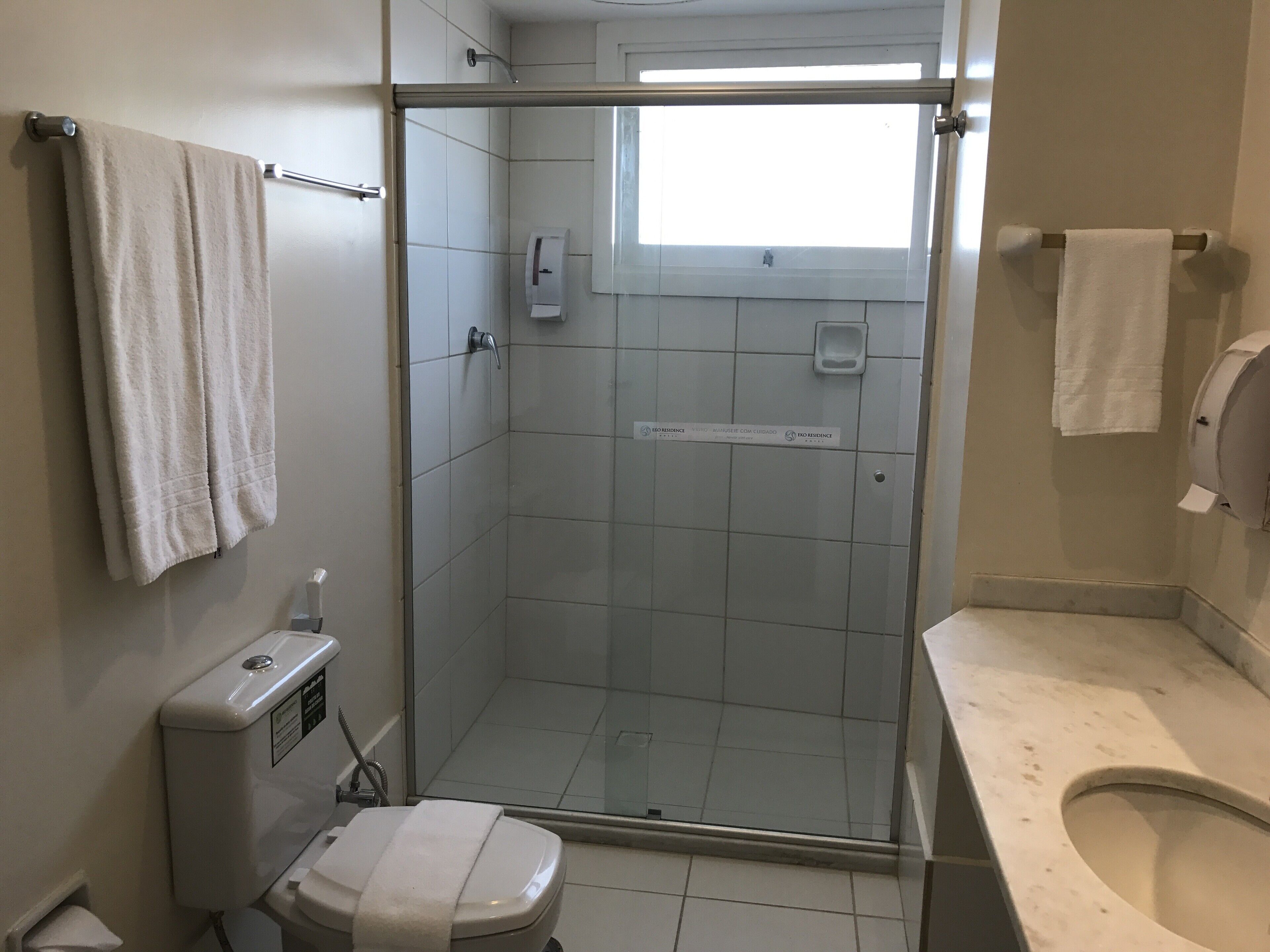 Une salle de bain avec une douche à parois de verre, des toilettes et un lavabo.