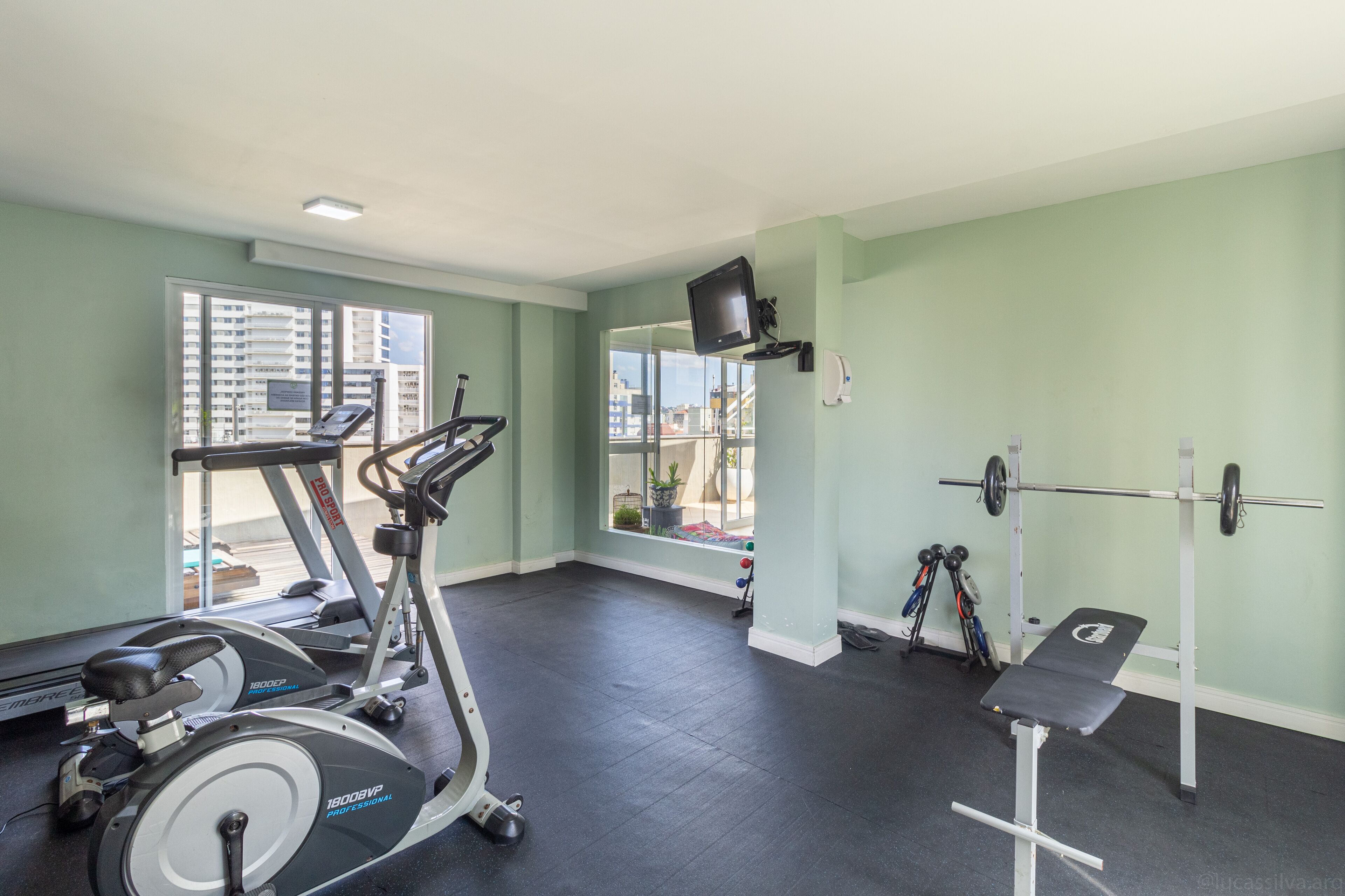 A gym with exercise equipment, a window, and a view of buildings.